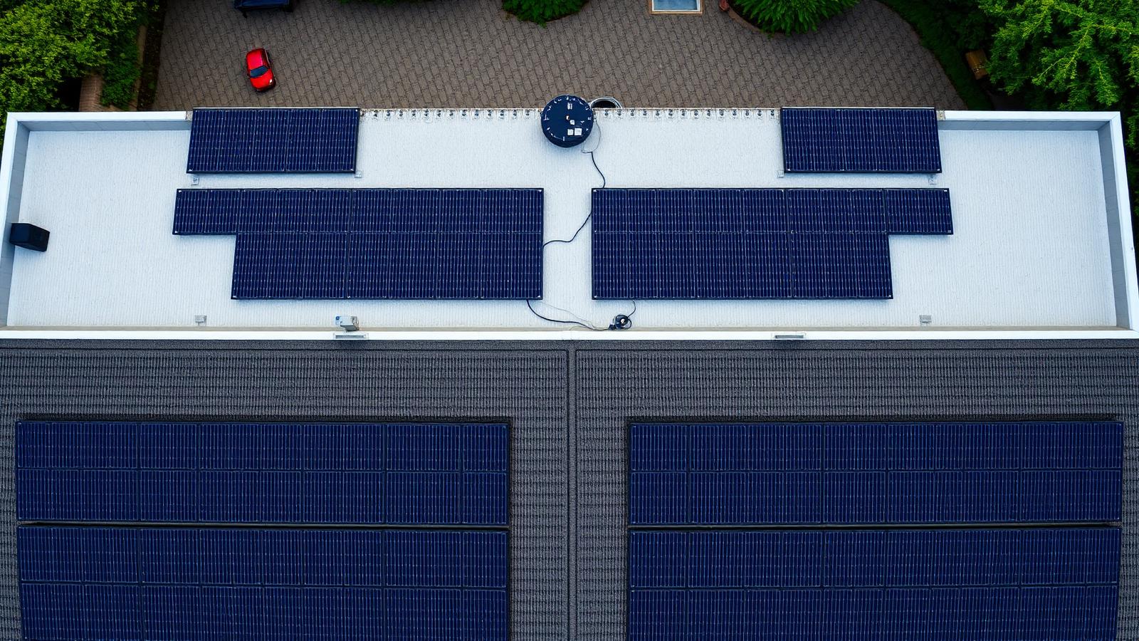 Vista aérea de un tejado residencial con una retícula ordenada de paneles solares oscuros